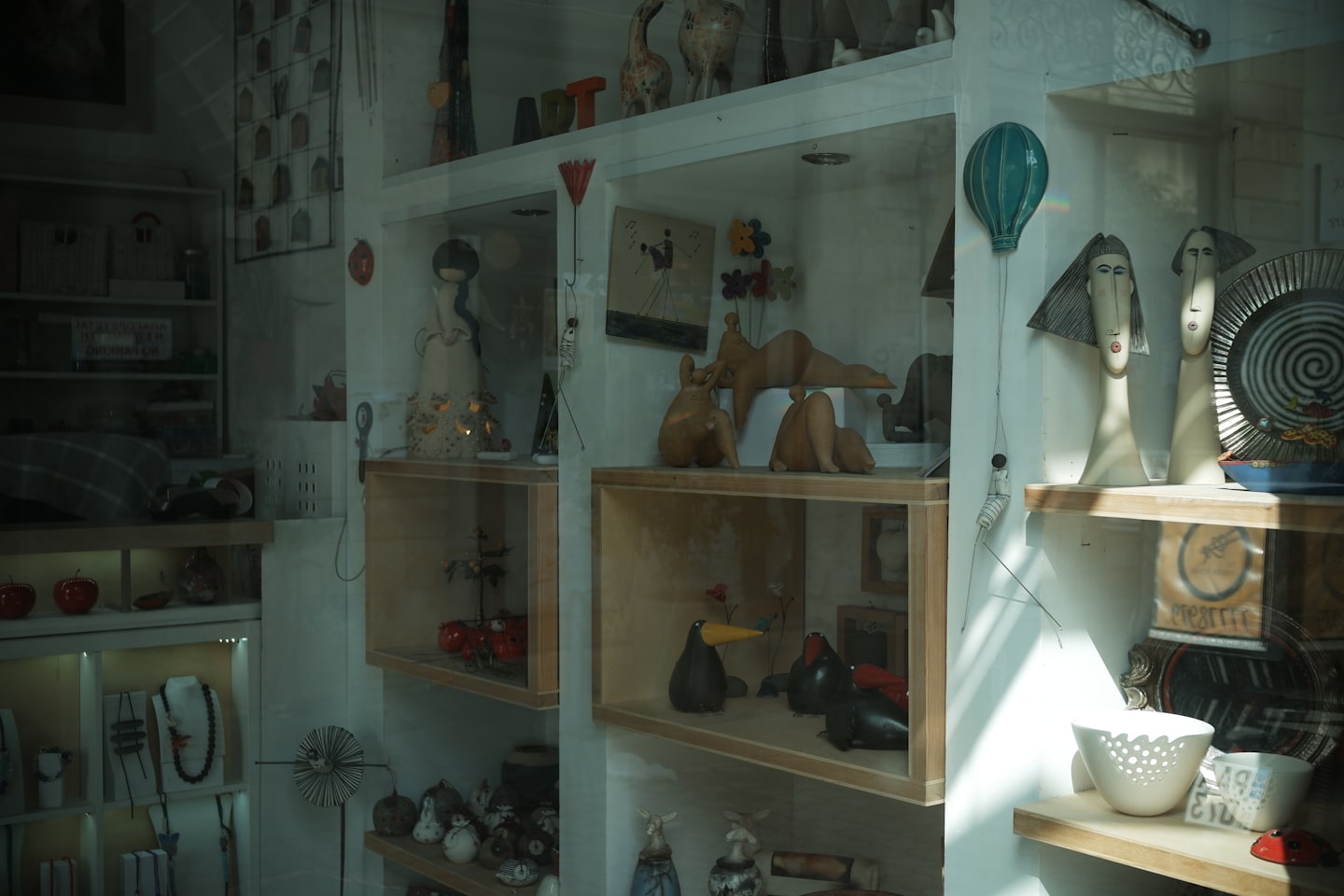 Handcrafted sculptures displayed on wooden shelves inside a boutique shop.
