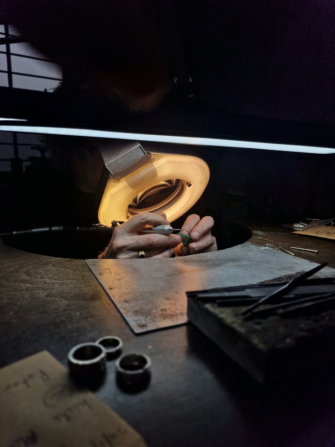 Hands use a rotary tool on a small metal object.