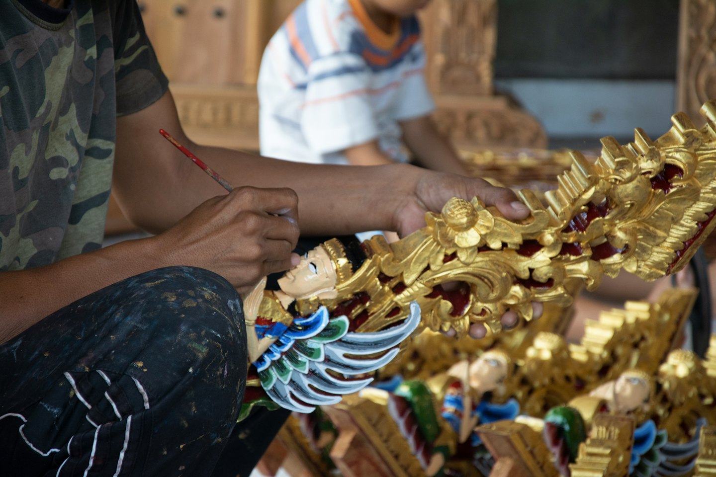 Artisan hand-painting details on a gilded wooden sculpture.