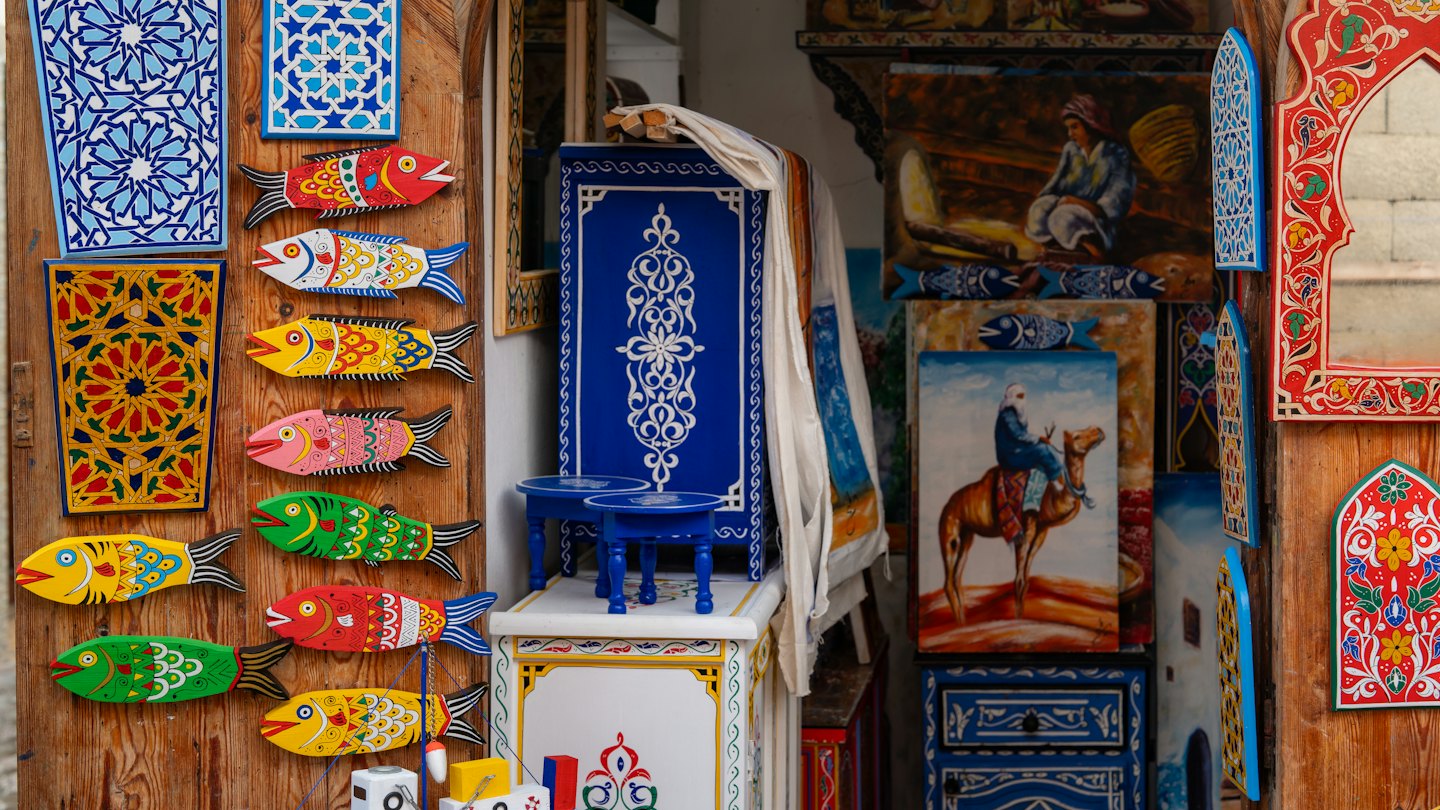 Handcrafted wooden fish and patterned tiles displayed on a market stall.